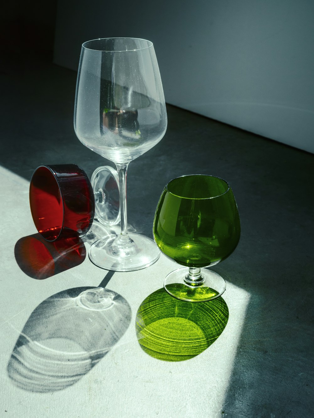 three different colored wine glasses sitting on a table