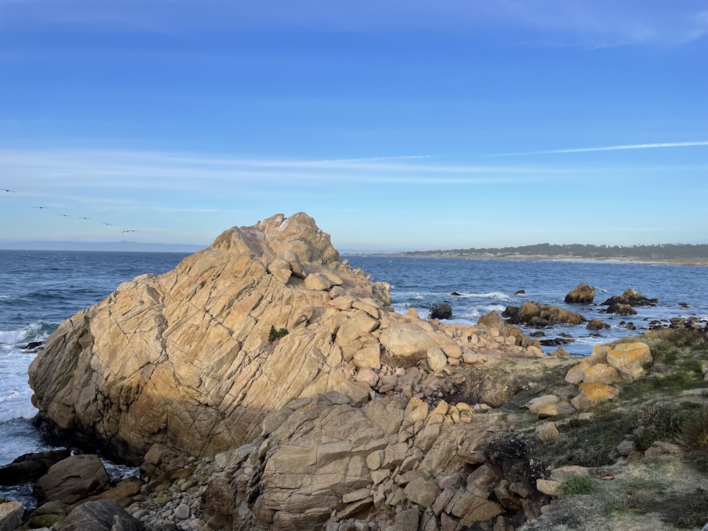 a large rock sitting on top of a beach next to the ocean