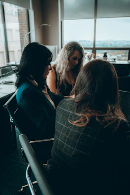 A group of professional women networking in a modern office with a view of the Riviera Maya coastline.