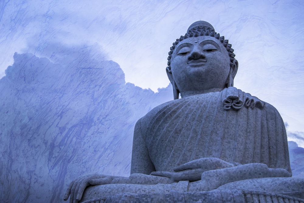 a statue of a buddha sitting in front of a mountain