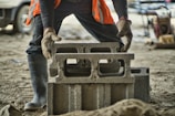 a man in an orange vest is working on a concrete block