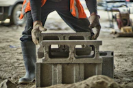 a man in an orange vest is working on a concrete block