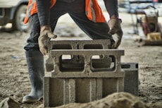 a man in an orange vest is working on a concrete block