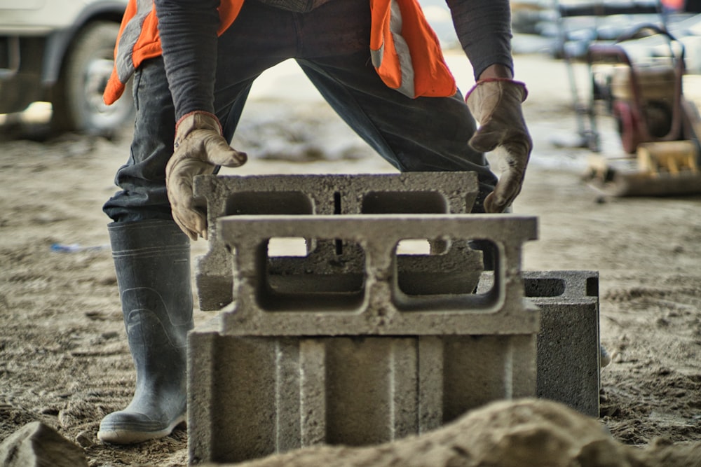 a man in an orange vest is working on a concrete block