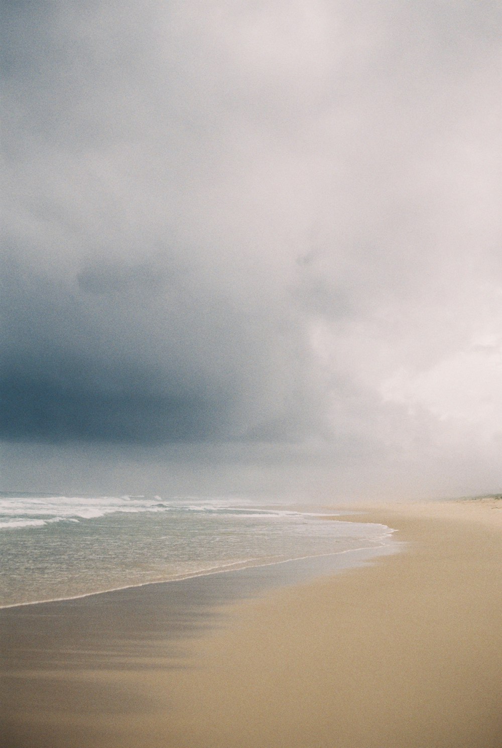 a person walking on a beach with a surfboard