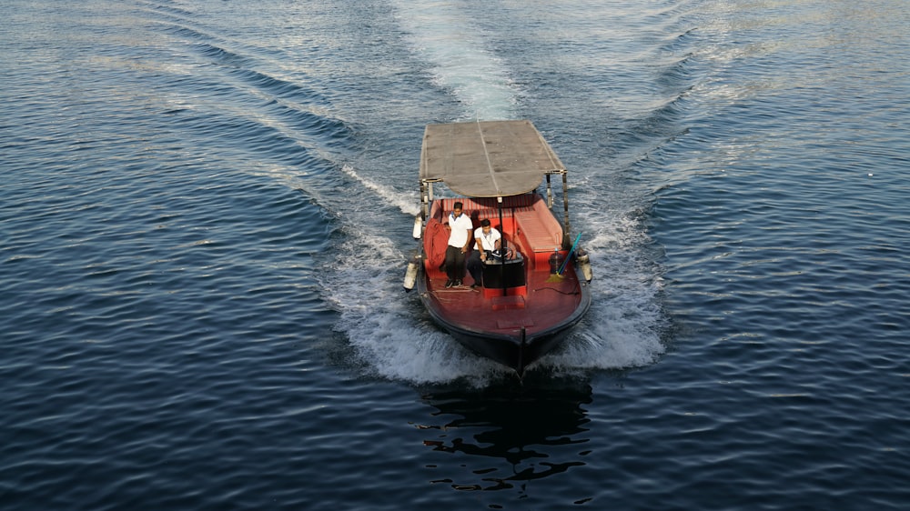 a red boat with two people riding on it's back