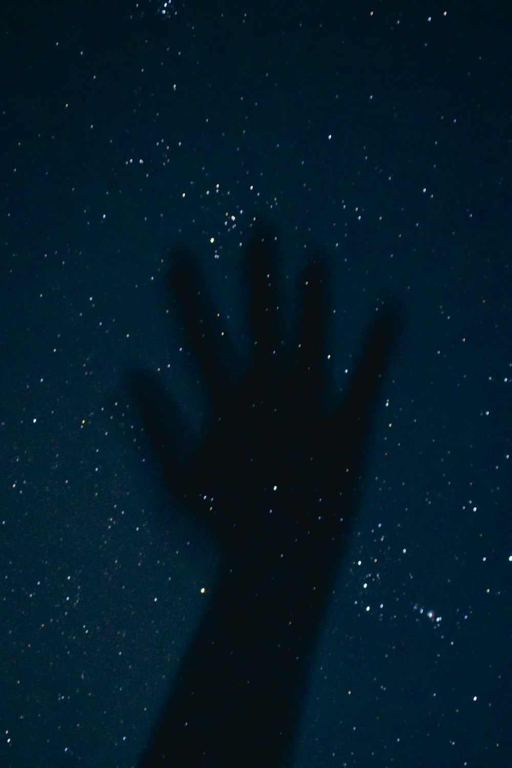 a person's hand is silhouetted against the night sky
