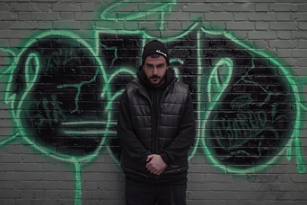 a man standing in front of a wall covered in graffiti