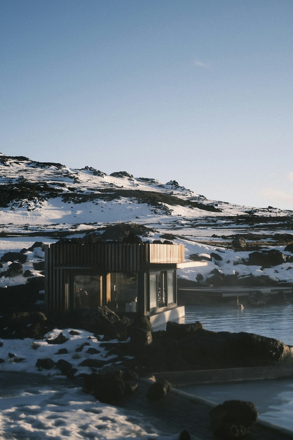 a small building sitting on top of a snow covered hillside