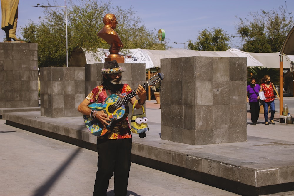 a man playing a guitar in front of a statue