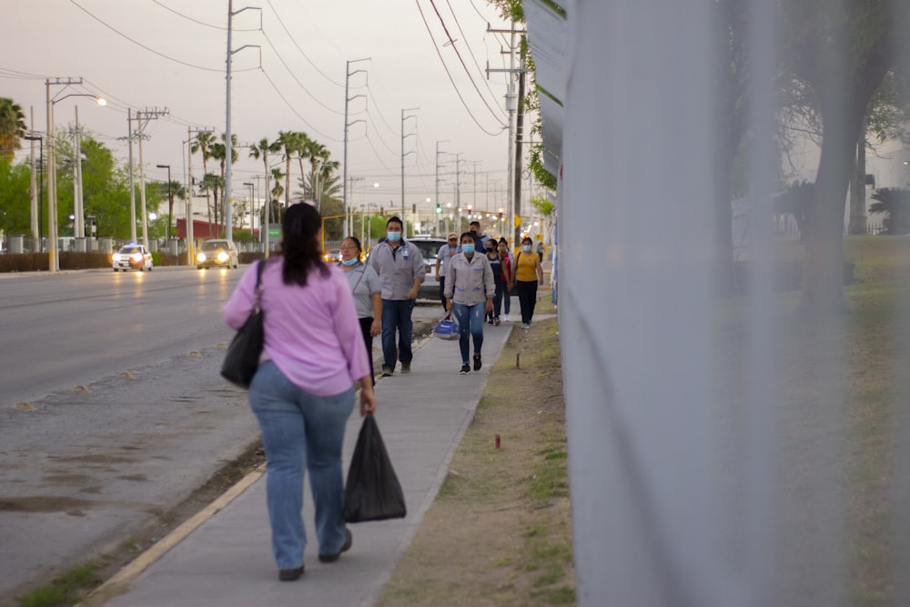 a group of people walking down a sidewalk