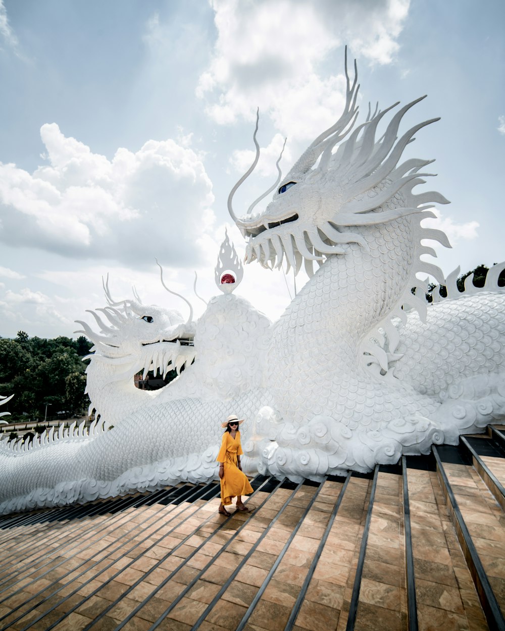 Una mujer parada frente a una estatua de dragón blanco