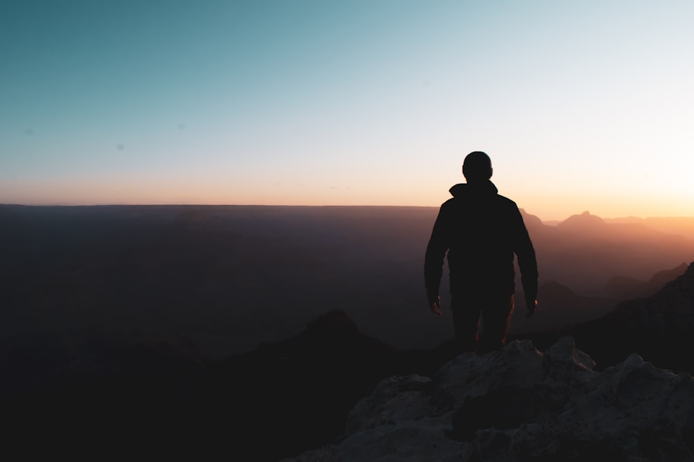 a man standing on top of a mountain at sunset