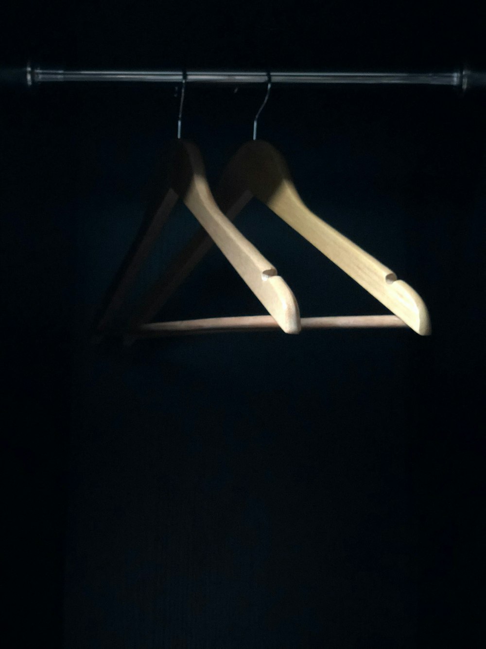 a pair of wooden clothes hangers in a dark room