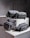 Four grey bags are arranged on a pair of concrete blocks. The bags have minimalistic design features, including black zippers and straps.