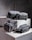 Four grey bags are arranged on a pair of concrete blocks. The bags have minimalistic design features, including black zippers and straps.