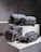 Four grey bags are arranged on a pair of concrete blocks. The bags have minimalistic design features, including black zippers and straps.
