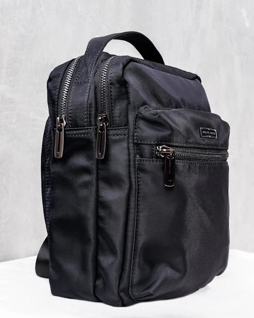 Close-up of a sleek black backpack with multiple compartments open, showing organized storage.