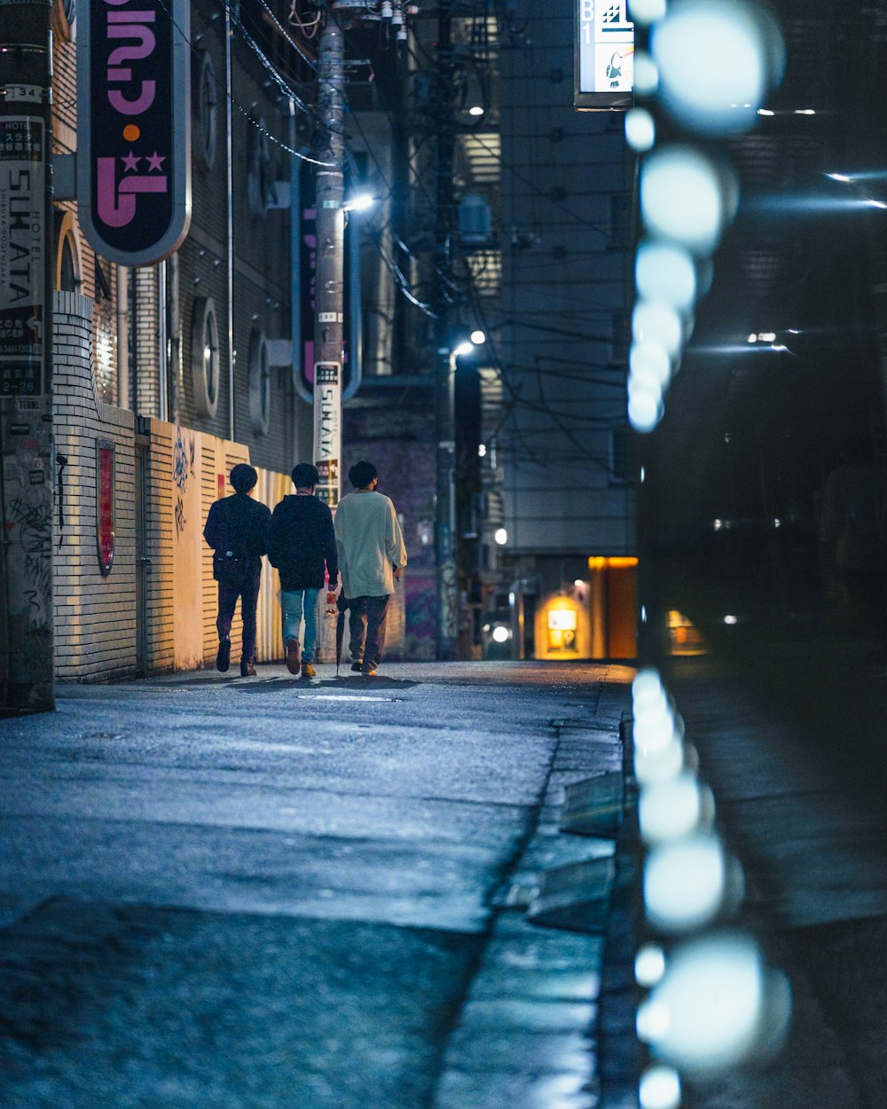 a group of people walking down a street at night