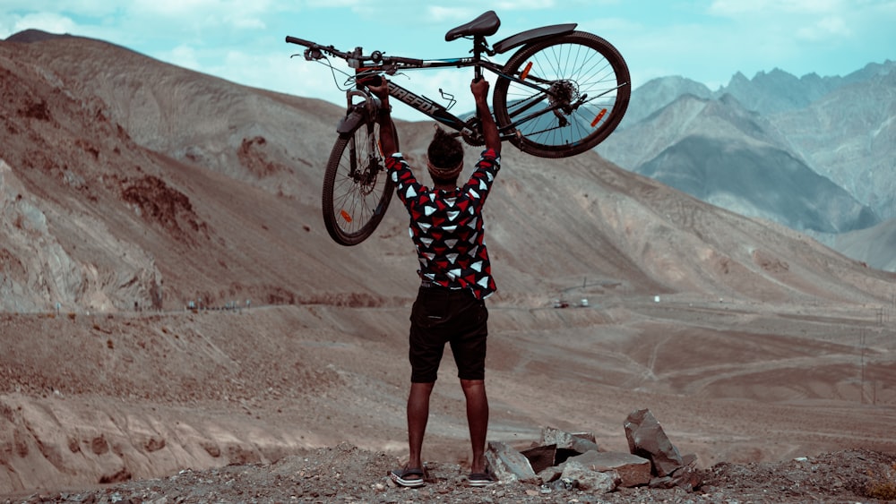 a man holding a bike on his shoulders