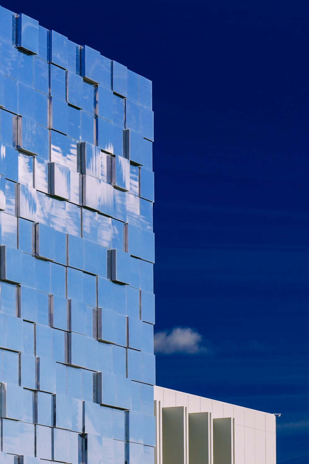 a tall blue building with a sky background