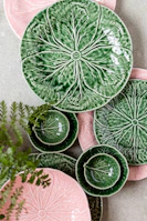 A set of stacked stoneware plates in cheerful yellows and greens, arranged on a cozy linen cloth with a hint of natural greenery.