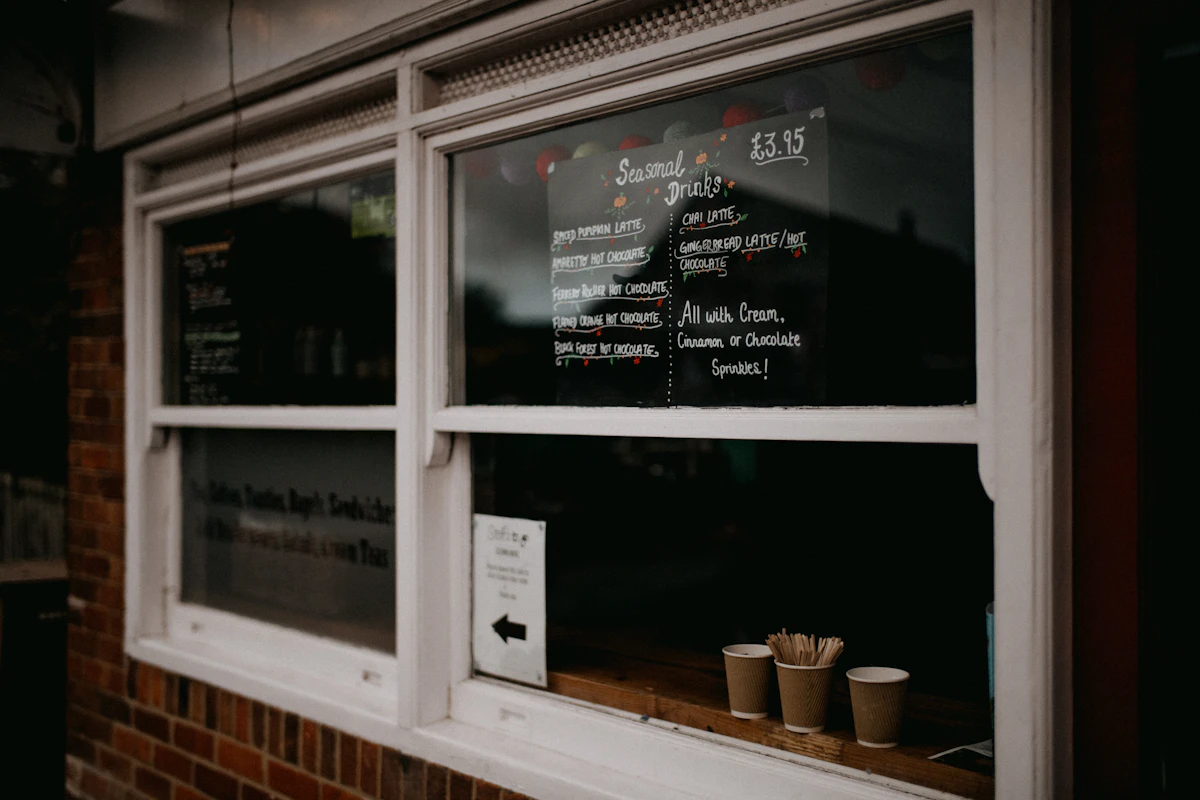 A faded, sun-bleached printed price list taped inside a small business shop window