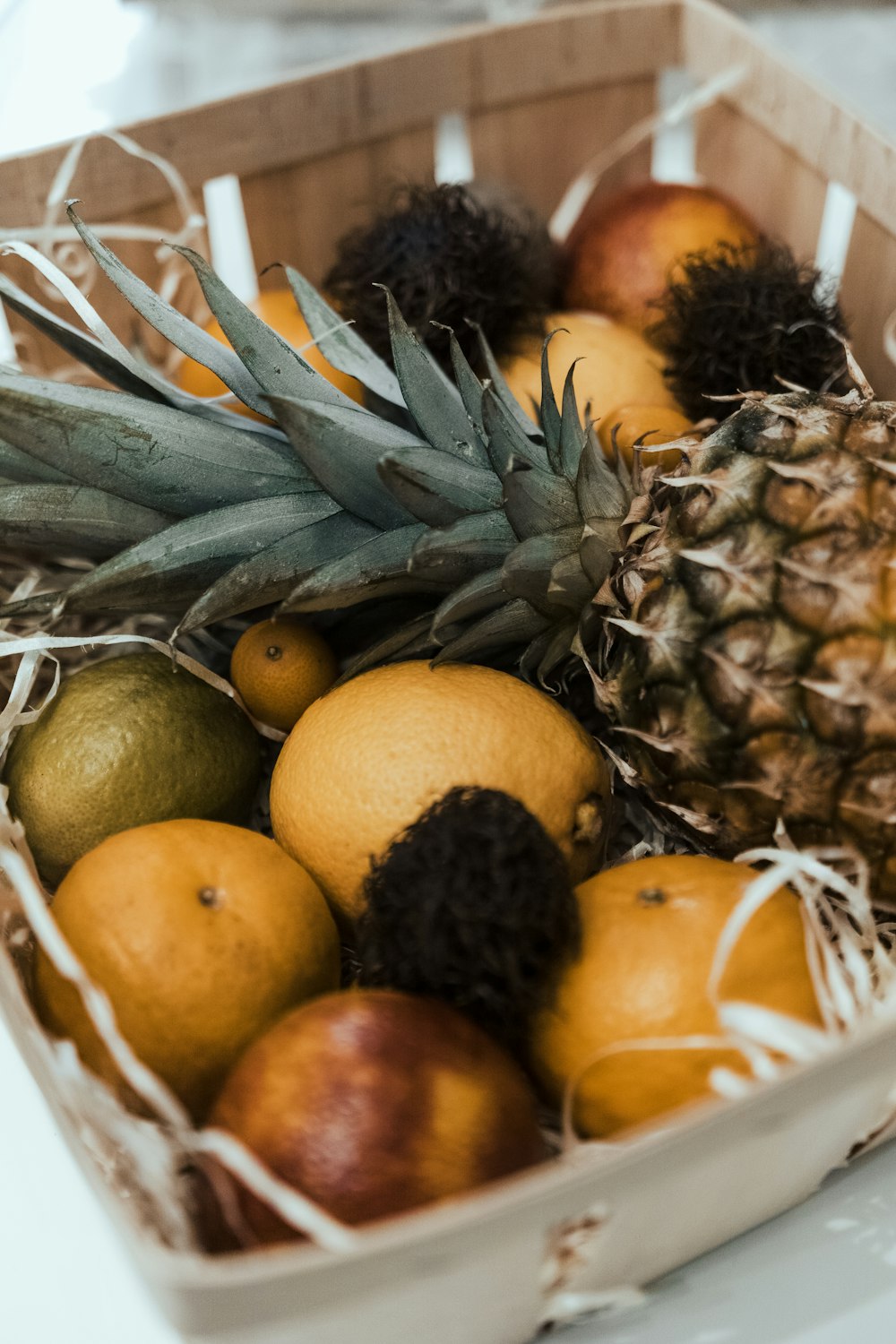 a pineapple, oranges, and other fruit in a box