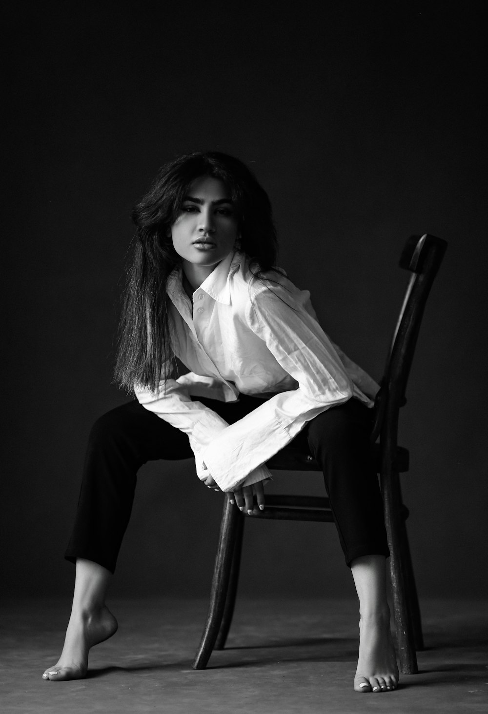 a woman sitting on top of a wooden chair