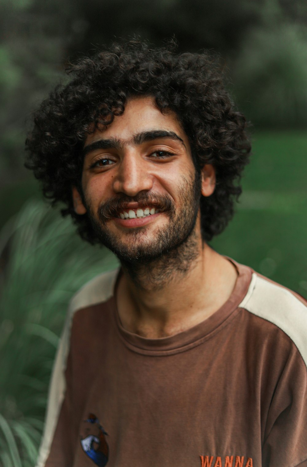 a man with curly hair and a beard smiling