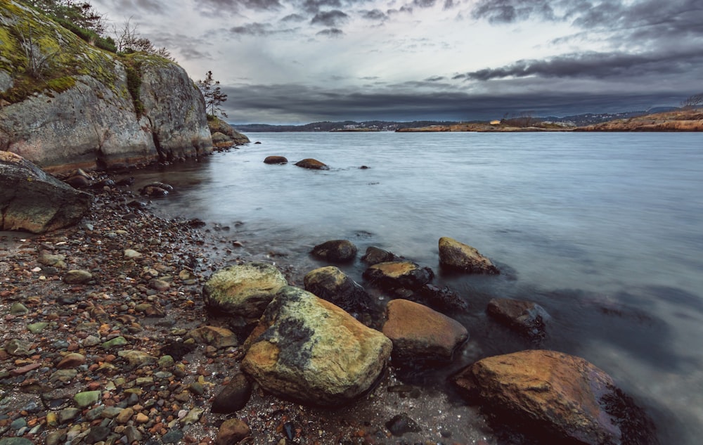 a rocky beach with rocks and water under a cloudy sky