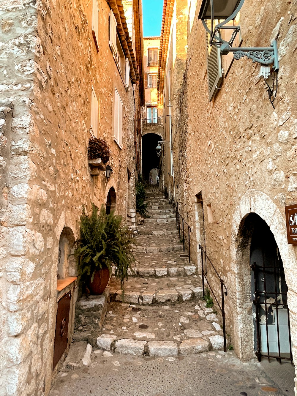 a narrow alleyway with stone steps and potted plants