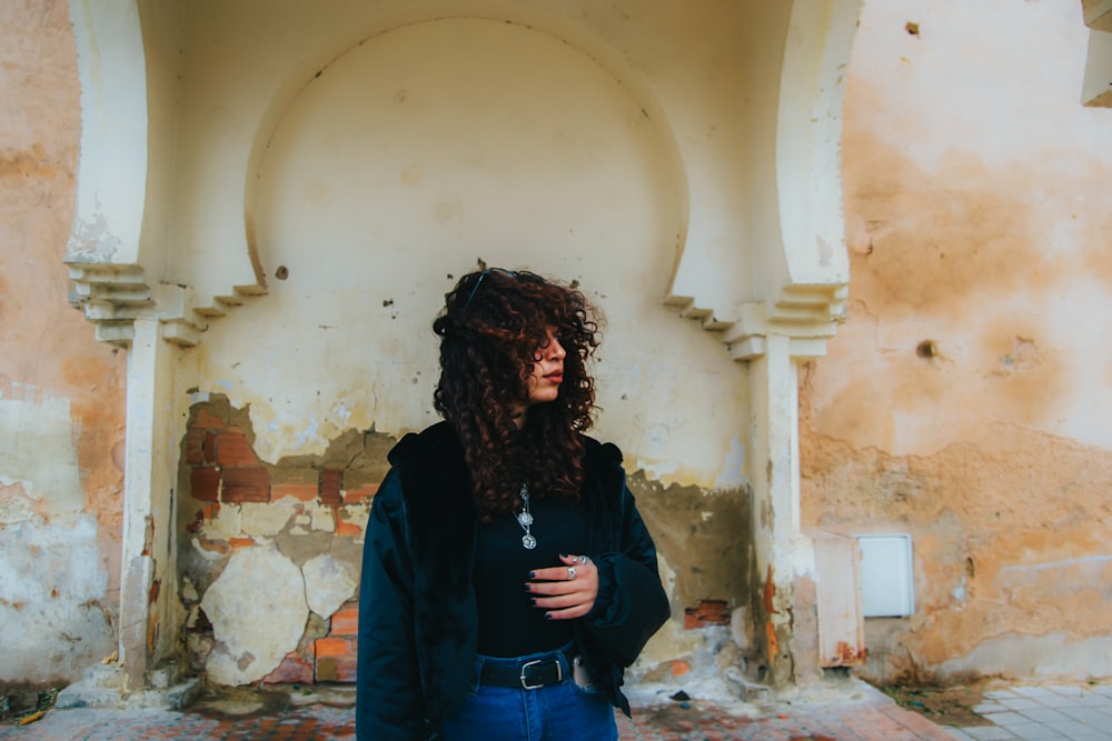 a woman with curly hair standing in front of a building