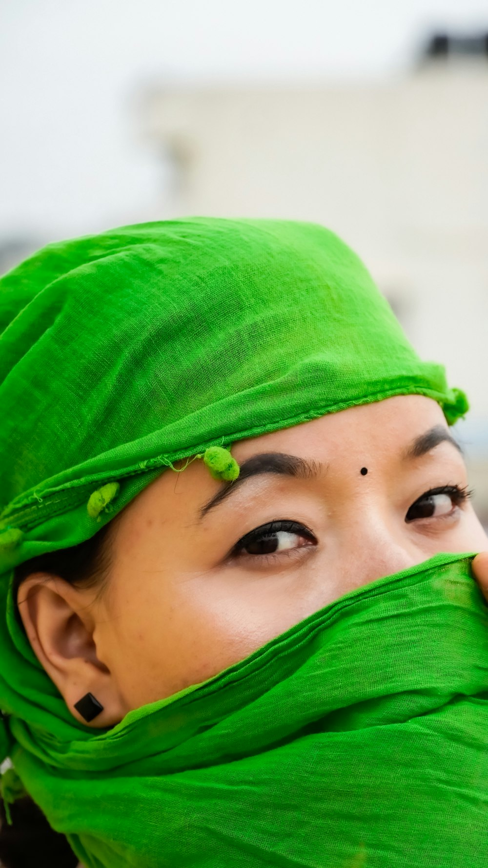 a woman with a green head covering covering her face