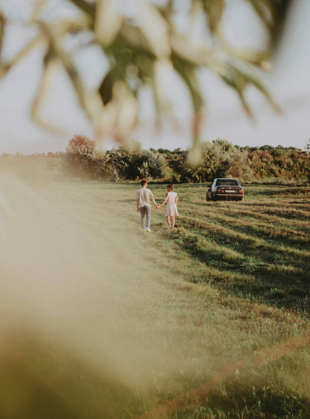 um casal de pessoas andando através de um campo coberto de grama