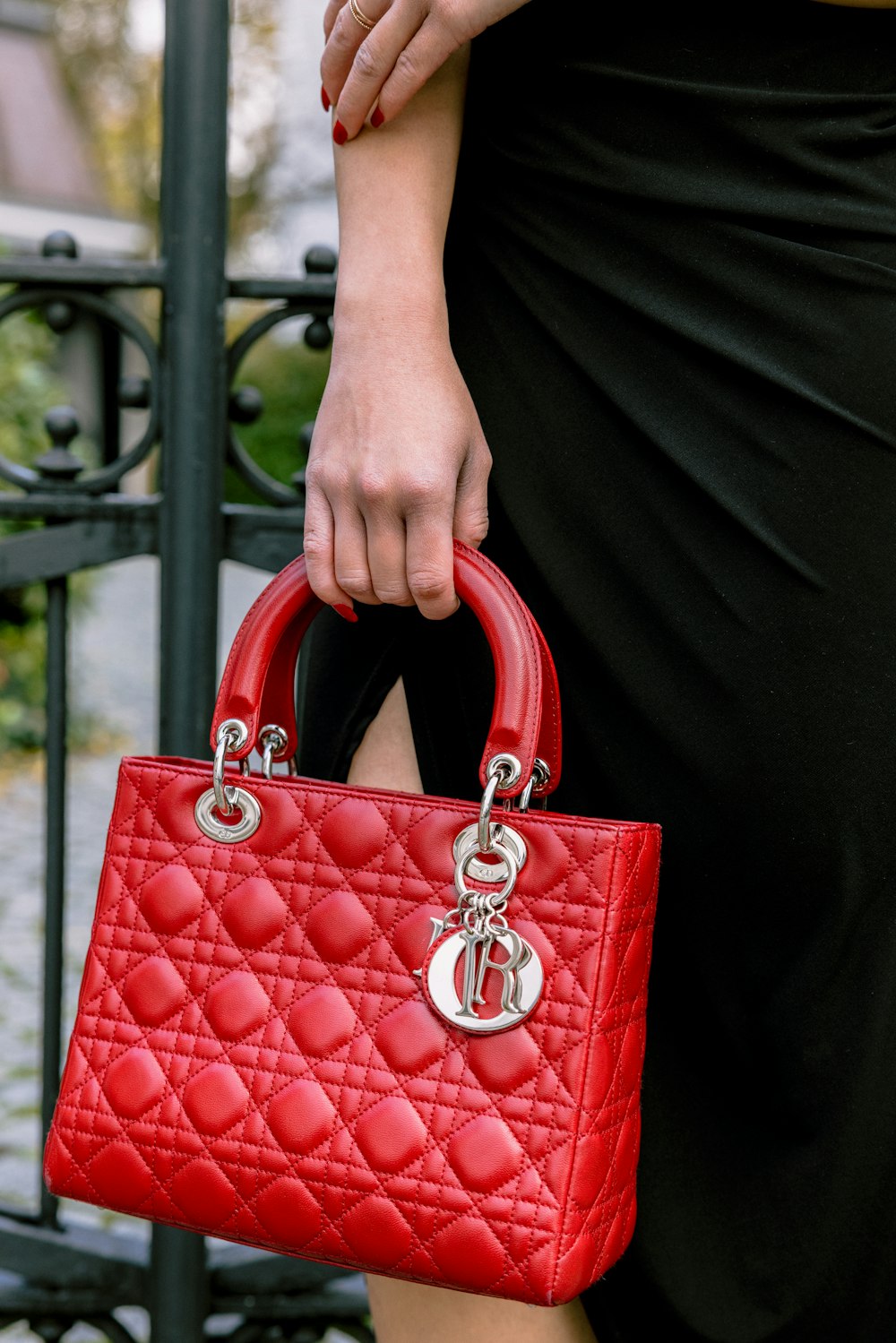 a woman in a black dress holding a red purse