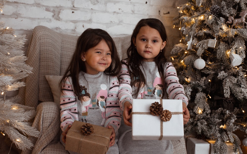 two little girls sitting on a couch with presents