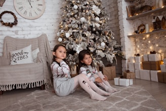 A warm Christmas scene showing children receiving gifts in a cozy room decorated with holiday lights.