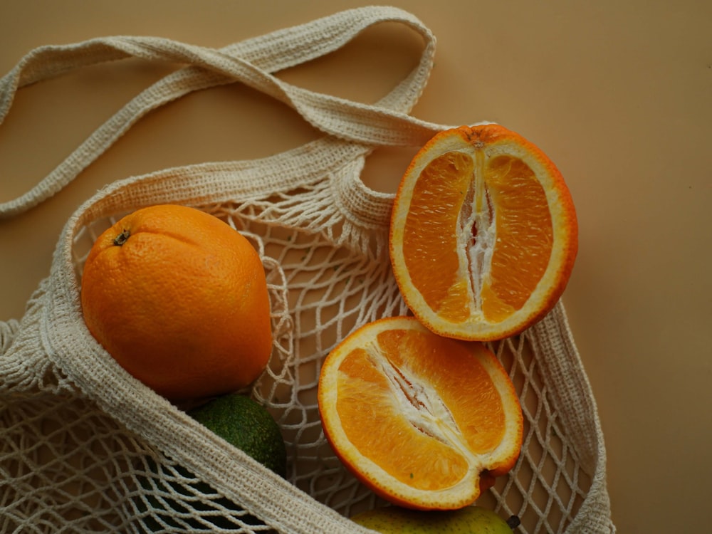 two oranges and one avocado in a bag