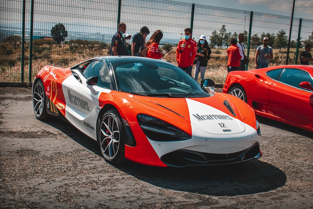 two orange and white sports cars parked next to each other