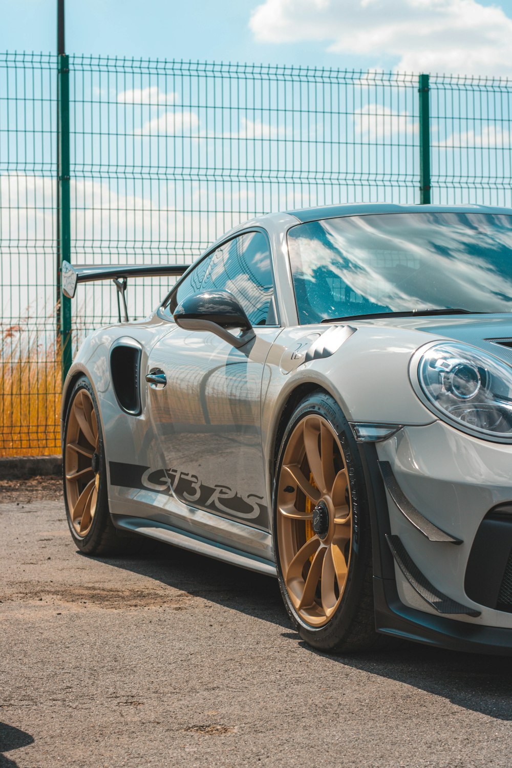 a silver sports car parked in front of a fence