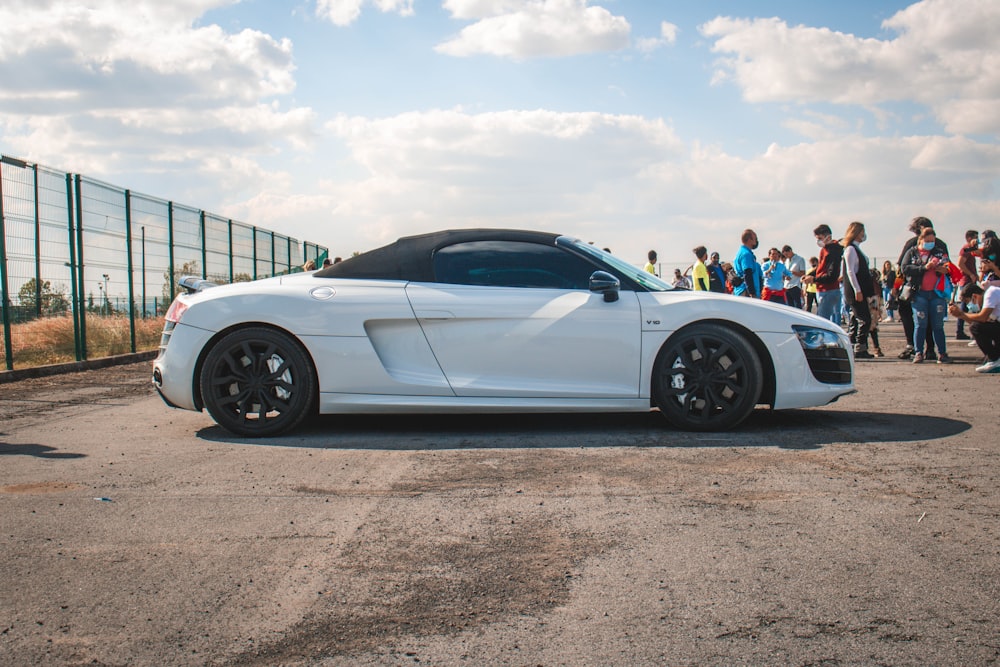 a white sports car parked in front of a group of people