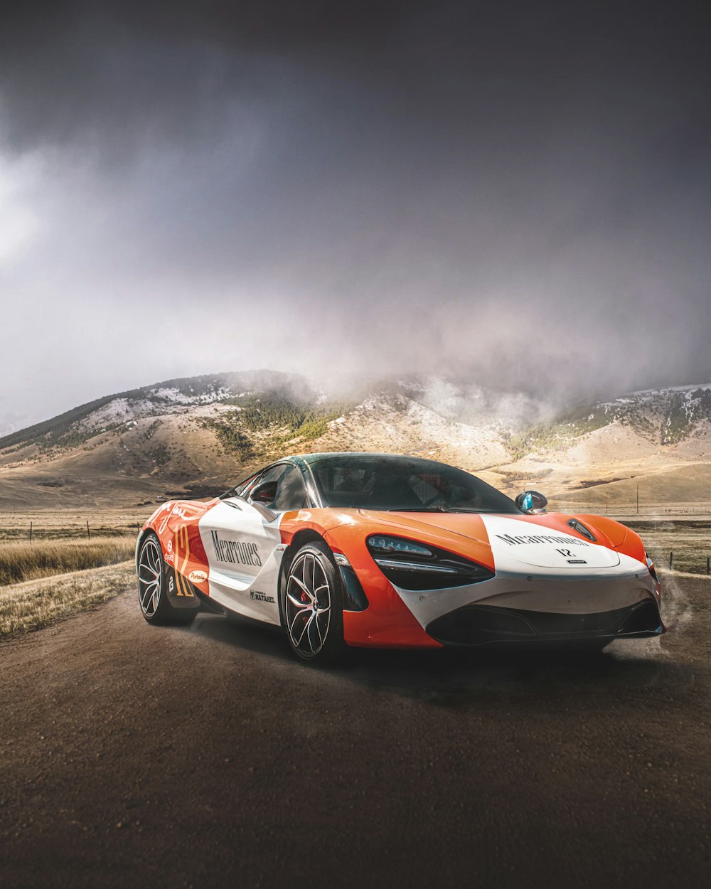 an orange and white sports car driving down a road