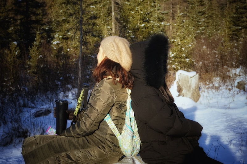 a couple of people sitting on top of a snow covered ground