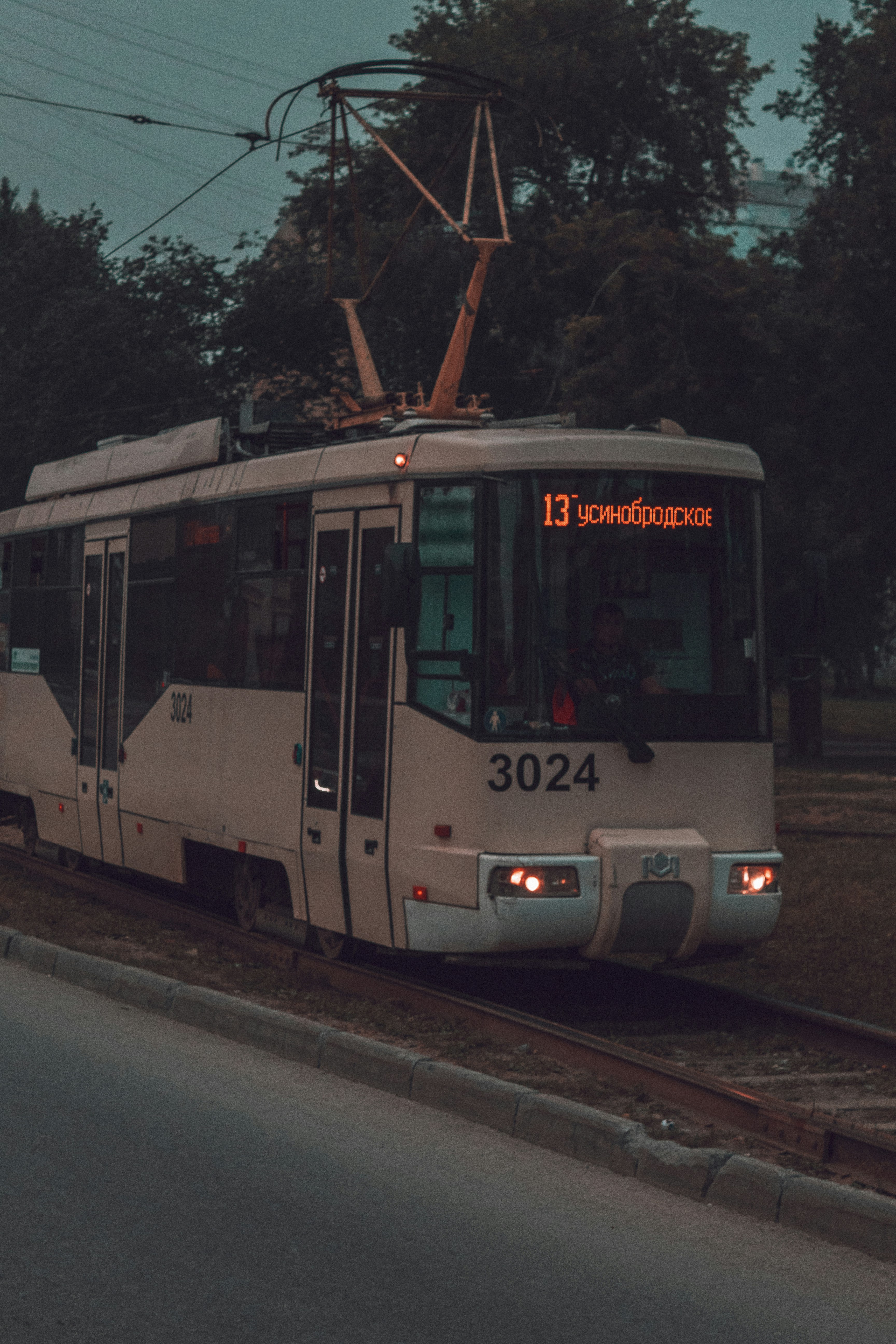a white train traveling down train tracks next to a forest