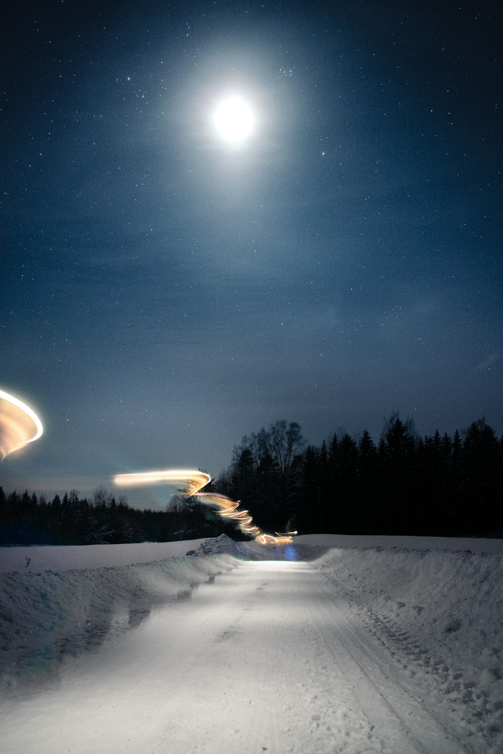 a snowboarder is going down a snowy road at night