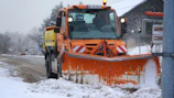 a snow plow driving down a snow covered road