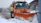Snow-covered driveway with clear paths and a bright orange snow removal truck in the background.