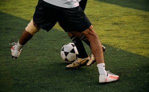 a man kicking a soccer ball on top of a field