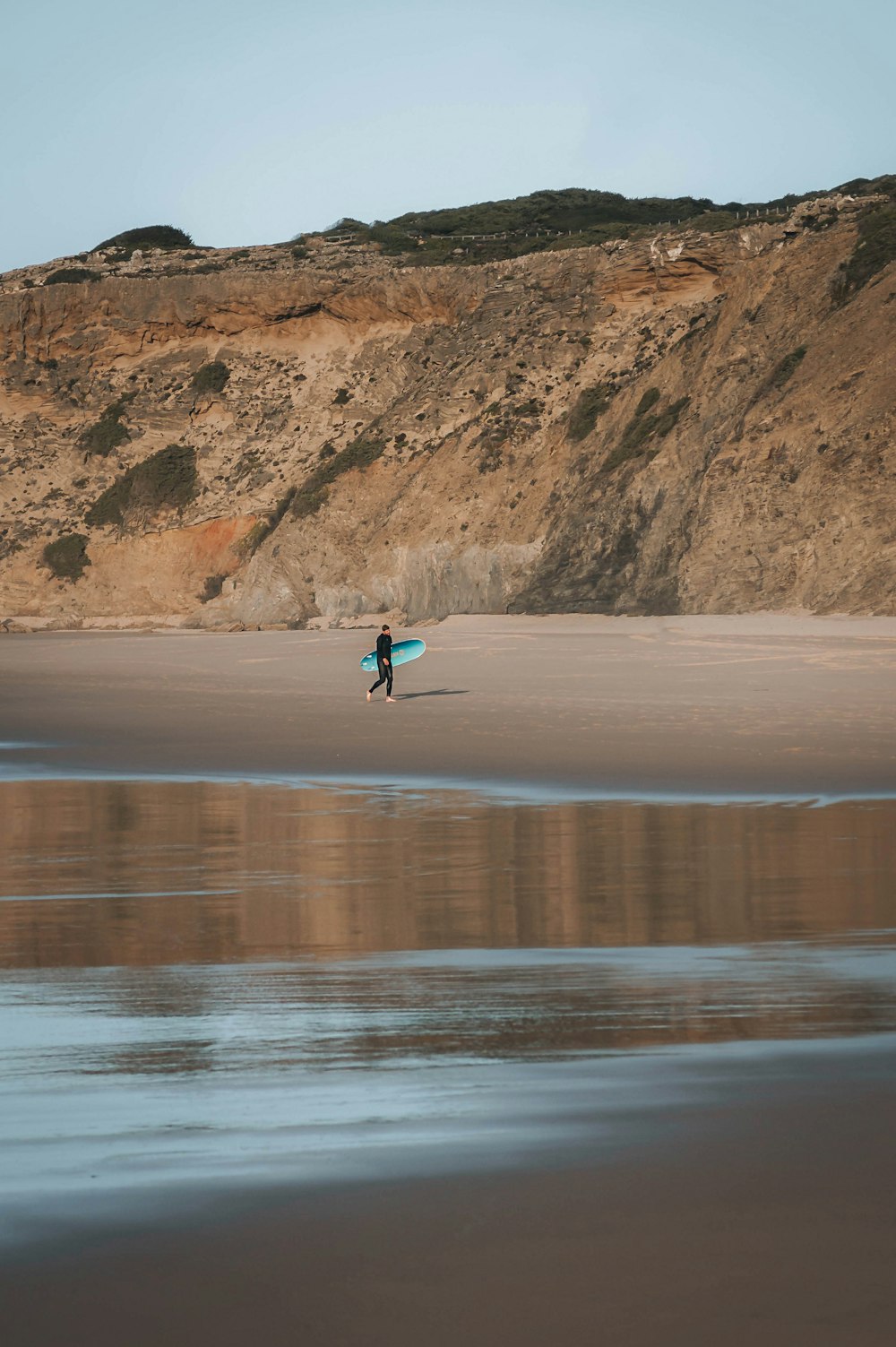 a person holding a surfboard on a beach